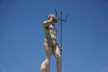 Vertical shot of Neptune statue against blue sky on sunny day at Fontana di Nettuno, Messina, Italy © Fernando Gabino/Wirestock Creators