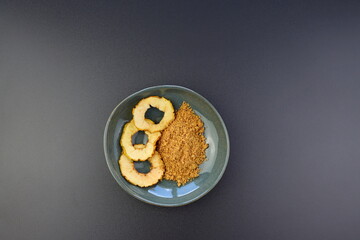 Dried apples and apple flour in a round bowl on a gray background.