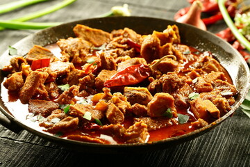 Homemade Indian beef curry roast cooked in iron skillet on wood fire. Traditional cokking concepts.