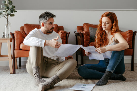 Puzzled couple reading documents on floor