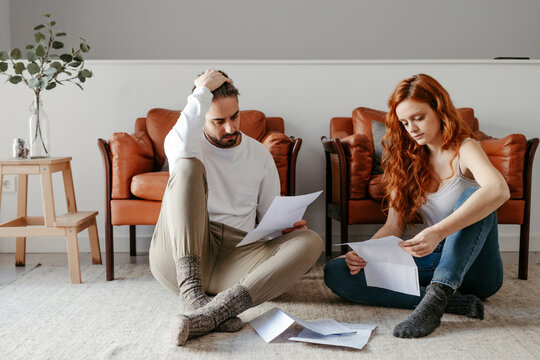 Puzzled couple reading documents on floor
