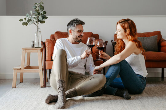 Loving couple with wineglasses sitting on floor