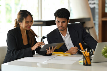 A portrait of good looking Asian businesspeople working together on a document and tablet in the office, for business and technology concept.