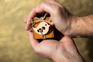 Fototapeta premium small wooden box in men's hands, offer of hands and hearts, a gift for a birthday