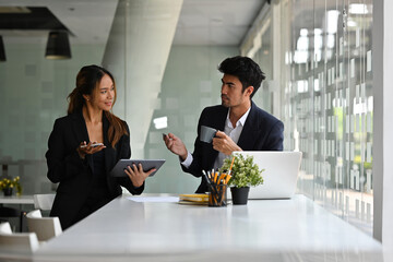 Portrait of Asian businesspeople working together on a document, a tablet and a laptop in the office, for business and technology concept.