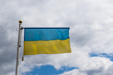 Ukrainian banner wave on the background of cloudy, dramatic sky. Picture taken in the day, sky full of clouds.