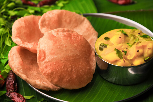 south indian famous breakfast poori or puri with potato curry served in a plate with banana leaf