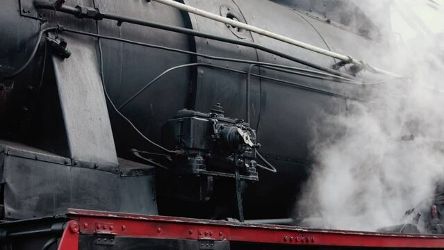 Vintage steam train locomotive. Pair locomotive train leaking smoke, steam ignited from behind. Antiquarian black steam engine. Old vintage train on the railroad. Close-up