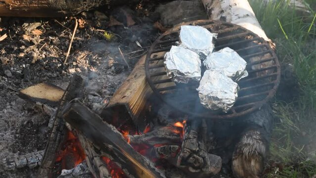 Campfire roasting cheese in alu foil bbq fire, hermelin type