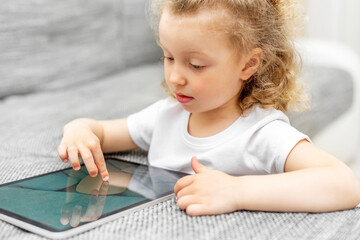 The child enthusiastically plays on the tablet.