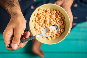 Top view of a man's hands holding a spoon full of breakfast cereal