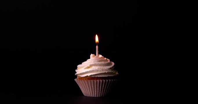 Tasty birthday cupcake with burning candle on black background