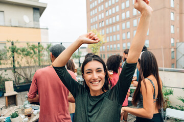 happy young woman with raised arms while dancing at university students party