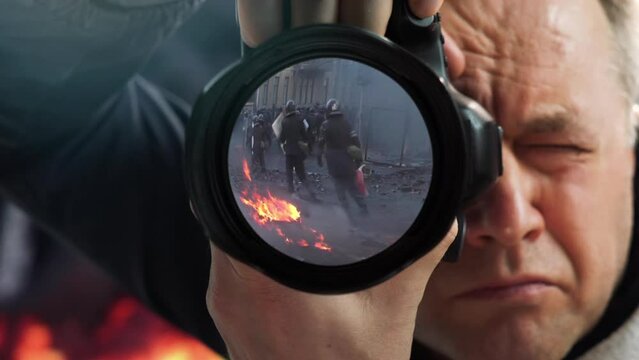 A journalist at war. A professional photojournalist shooting a report about a war, a terrorist attack or a man-made disaster in the middle of burning buildings at the risk of life