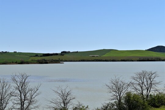 Santa Luce lake in the Tuscan countryside with blue sky and green hills