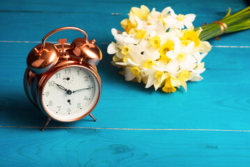 Vintage mechanical alarm clock with yellow daffodils on a blue wooden background. Good morning, we are from Ukraine