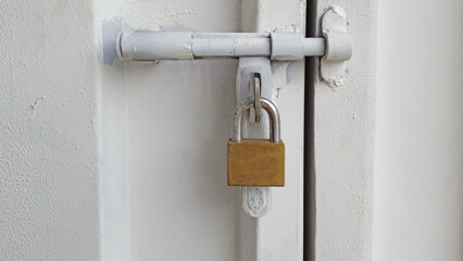 The white iron door is locked with a large padlock.