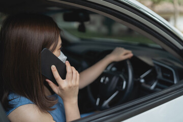 Plakat Asia woman using mobile phone while driving woman is calling insurance or someone to help when the car breaks down or has an accident.