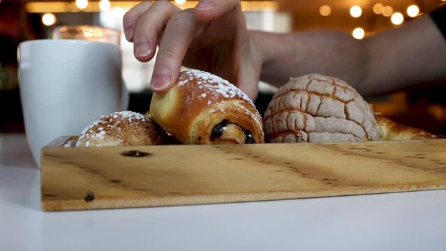 Choosing a Pan de Chocolate from a Basket of Bread