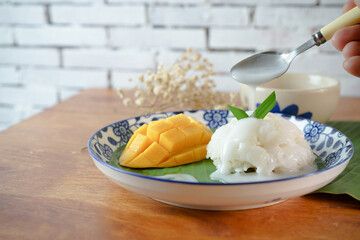 Sticky Rice with Ripe Mango in Coconut Milk Authentic Thai desserts on a wooden table