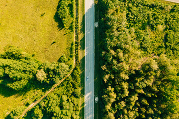 Aerial shot of cars on a highway during daytime with a green field and a forest from right and left - Powered by Adobe