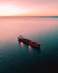  Aerial shot of a red tanker cargo ship on the sea during sunset © Sander Peterson/Wirestock Creators