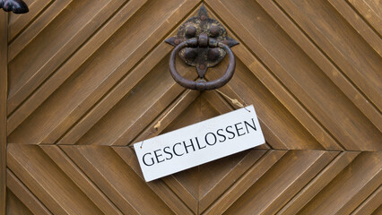 Schild mit der Aufschrift GESCHLOSSEN hängt an einer Holztür von einem Geschäft
