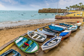 Fototapeta na wymiar A view of boats beside the beach near to the castle in the city of Cadiz on a spring day