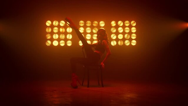 Dancer girl practicing streaptease elements on chair. Blonde dancing sexually.