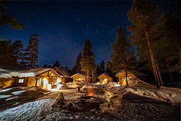 Fototapeta premium Northern Lights in the arctic winter with snow and chalets