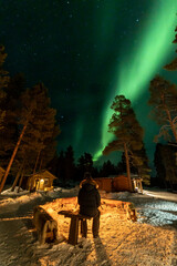 Northern Lights in the arctic winter with snow and chalets