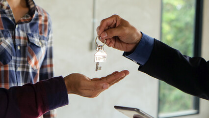 A man give a house key ring to the customer as business agency house rental buy or sell