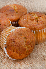 bunch of fresh home baked carrot and nut health muffins on rustic surface with hessian and copy space

