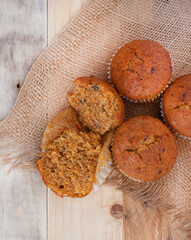 bunch of fresh home baked carrot and nut health muffins on rustic surface with hessian and copy space

