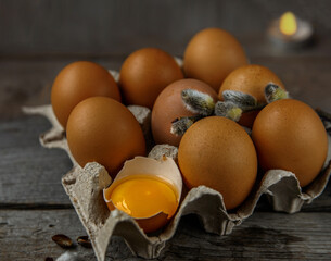 Paper box with chicken eggs and branch of willow. One egg broken