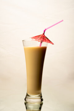 An elegant Cocktail drink with an umbrella and a straw isolated on a white background on a reflective surface with a perfect mirrored image.