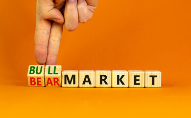 Bull or bear market symbol. Businessman turns wooden cubes and changes words Bear market to Bull market. Beautiful orange table orange background, copy space. Business bull or bear market concept.