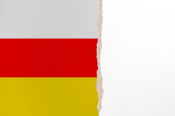 Half- ripped paper background in colors of national flag. South Ossetia
