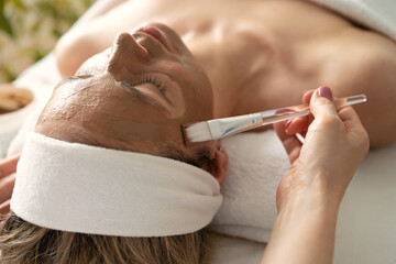 he face of a white woman undergoing cosmetic procedures. Brown clay face mask. Facial care....