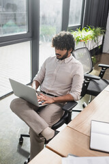 Young indian businessman using laptop in office.