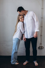 Couple in love hug and kiss each other. Happy young family at home in white t-shirts