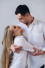 Fototapeta premium Couple in love hug and kiss each other. Happy young family at home in white t-shirts