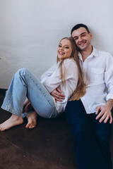 Couple in love hug and kiss each other. Happy young family at home in white t-shirts