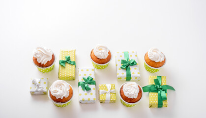 Top view present boxes and cupcakes on white background. Happy birthday banner.