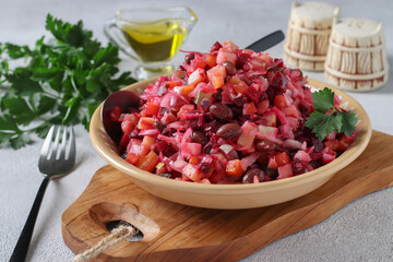 Traditional Salad Vinaigrette with beans, pickles, pickled cabbage and boiled vegetables in clay plate on wooden board, Close-up