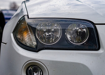 Headlight of new modern white car close up