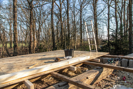 Dach decken mit Holzplatten. Leiter und Werkzeug mit Eimer auf dem Dach.