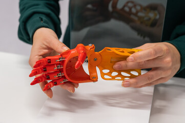 A woman demonstrates a plastic children's prosthetic hand printed on a 3D printer. 