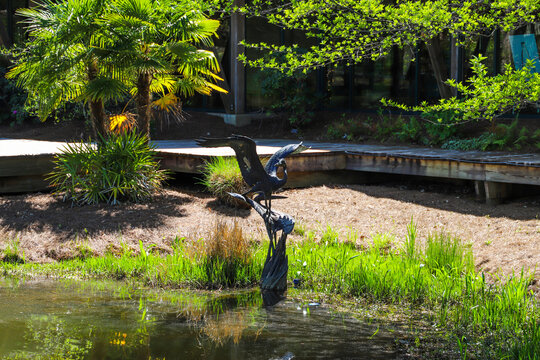 a bronze sculpture of a goose spreading its wings surrounded by a silky green lake and lush green trees, grass and plants at Callaway Gardens in Pine Mountain Georgia USA