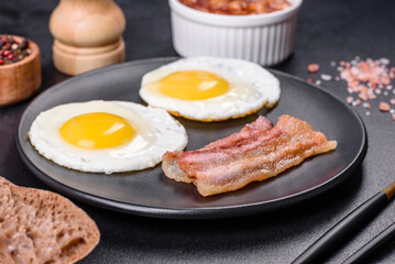 English breakfast with fried eggs, bacon, beans, tomatoes, spices and herbs